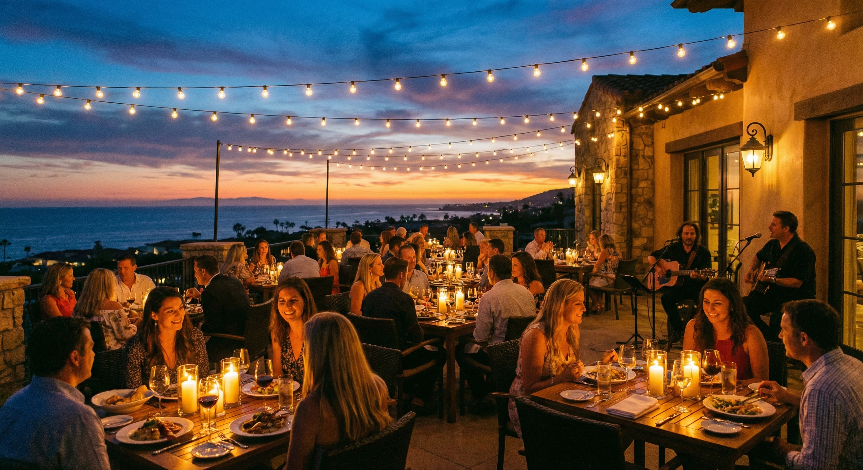 Outdoor dining terrace overlooking the ocean at dusk, string lights overhead